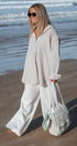 Woman in light clothing holding a white bag on a beach