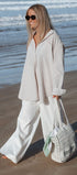 Woman in light clothing holding a white bag on a beach