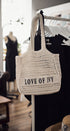 Crocheted bag with 'LOVE OF IVY' text hanging on a rack in a store setting.