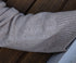 Close-up of a person wearing a beige sweater with embroidery
