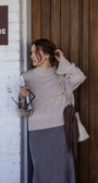 Woman adjusting her hair against a wooden wall with a store sign.