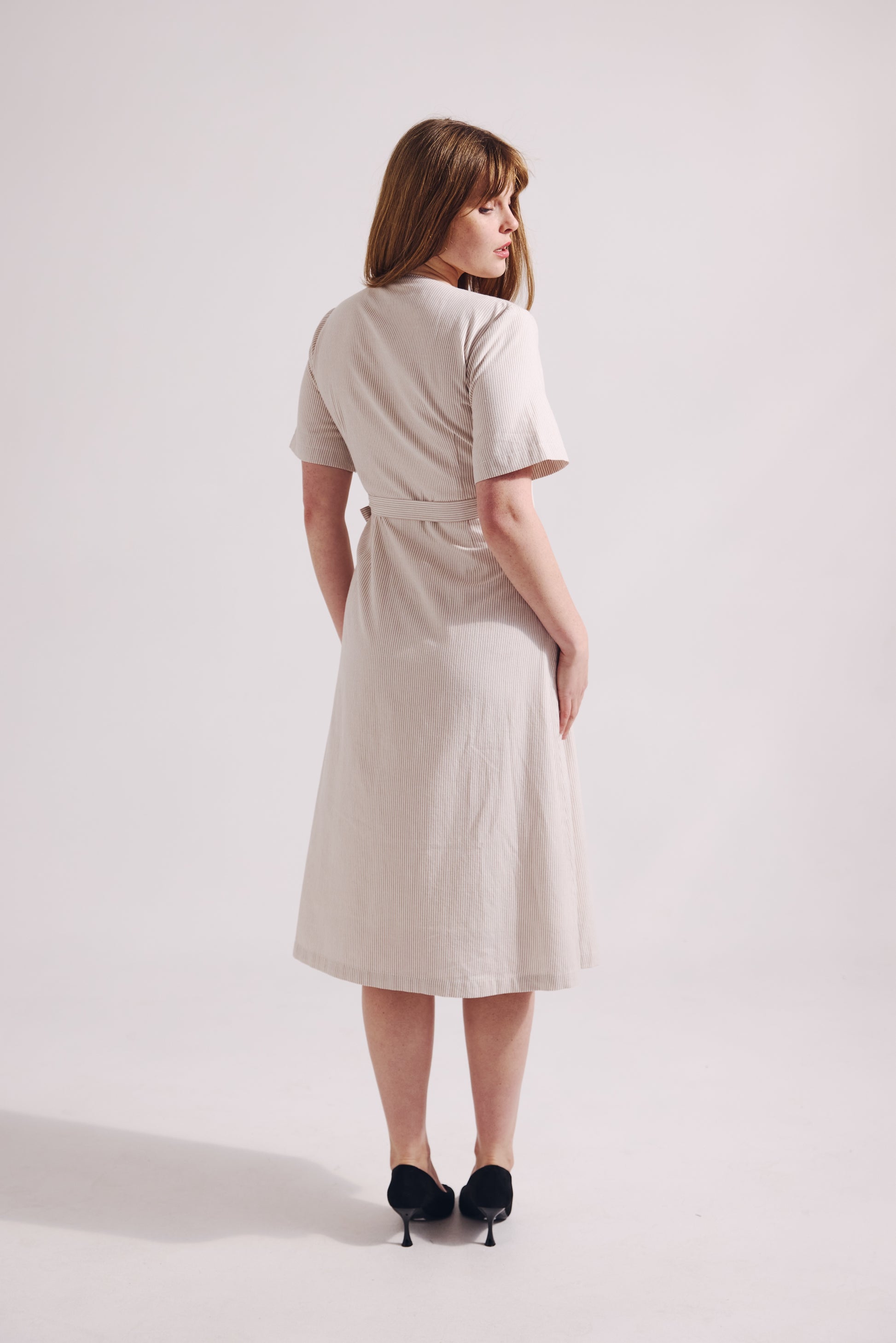Woman wearing a beige dress on a white background