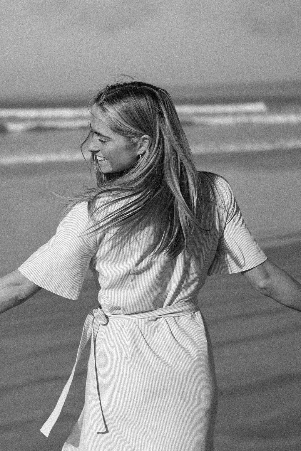 Woman standing on a beach with long hair flowing, black and white photo