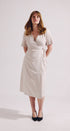 Woman wearing a white wrap dress on a plain background