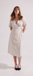 Woman wearing a white wrap dress on a plain background