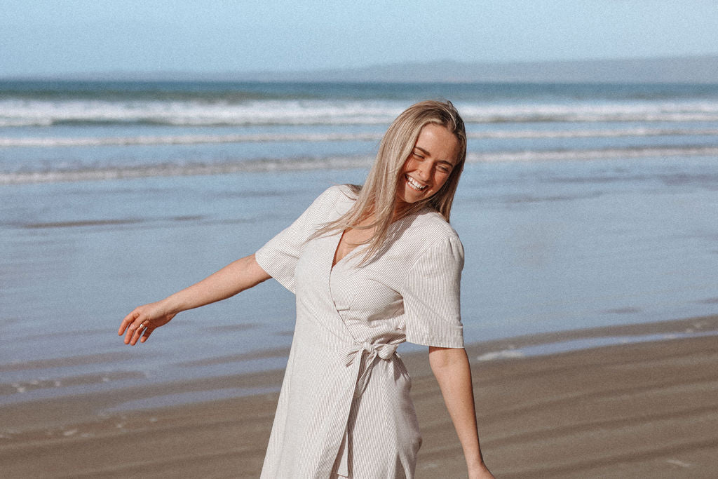 Woman in a white dress standing on a beach with ocean waves in the background