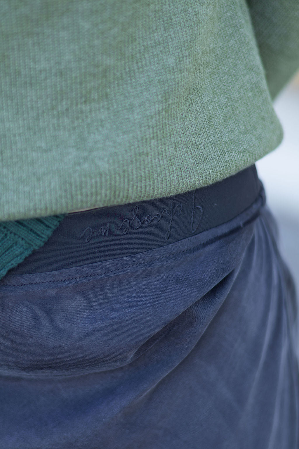 Close-up of a green sweater and blue pants with embroidery