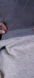 Close-up of a person adjusting a gray sweatshirt with embroidery.