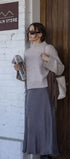 Woman standing outside a store named 'Gold Grain Store' holding a magazine.