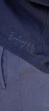 black knit top with 'Evolving Daily' embroidery on a blurred background