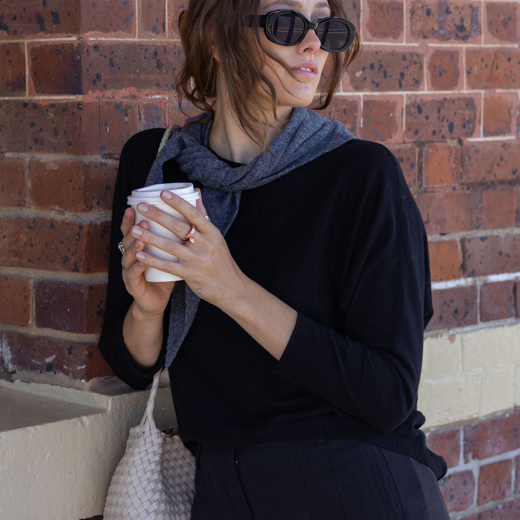 Woman holding a coffee cup against a brick wall