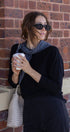 Woman holding a coffee cup against a brick wall