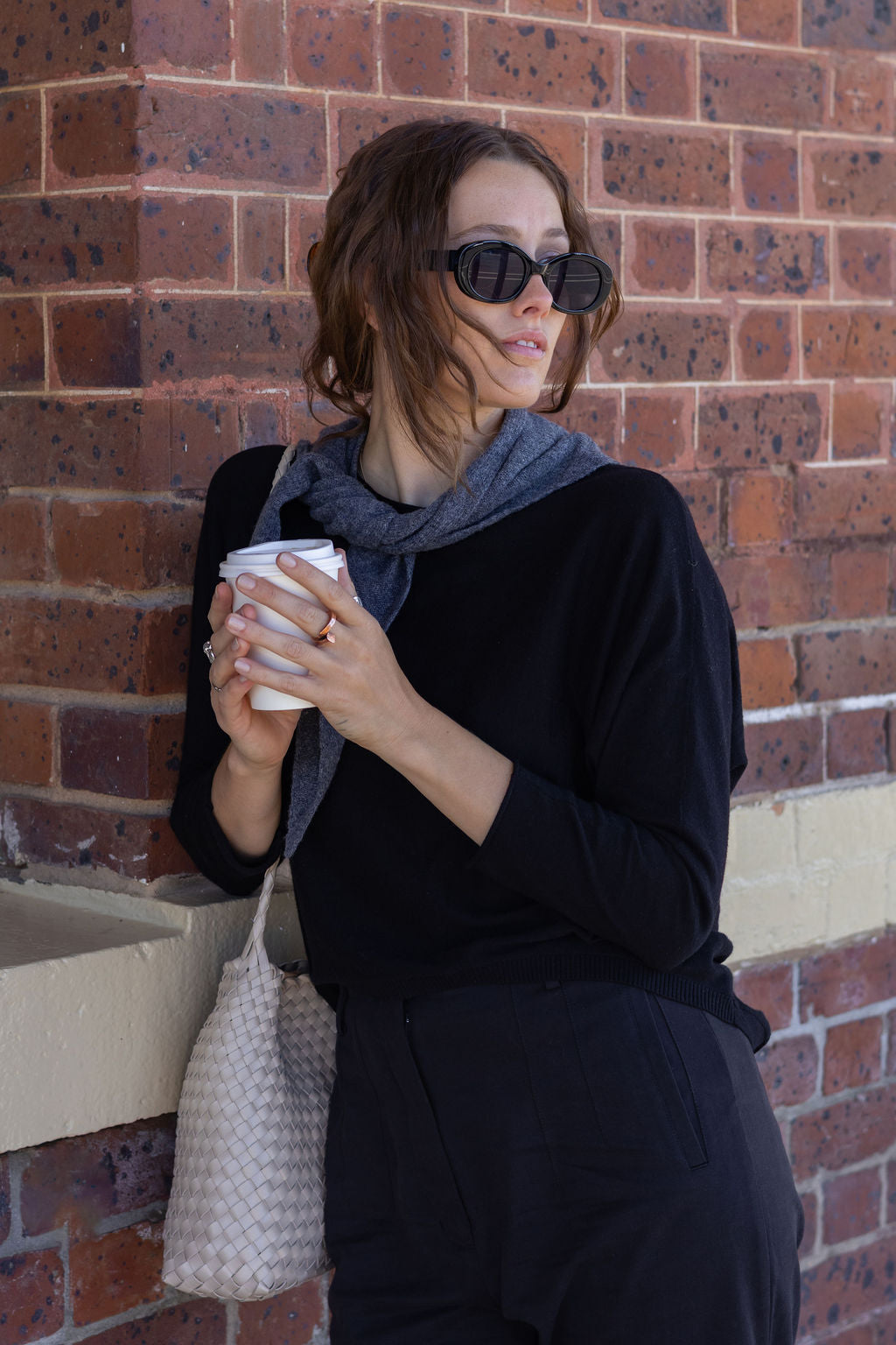 Woman holding a coffee cup against a brick wall