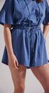 Blue romper worn by a person on a plain background