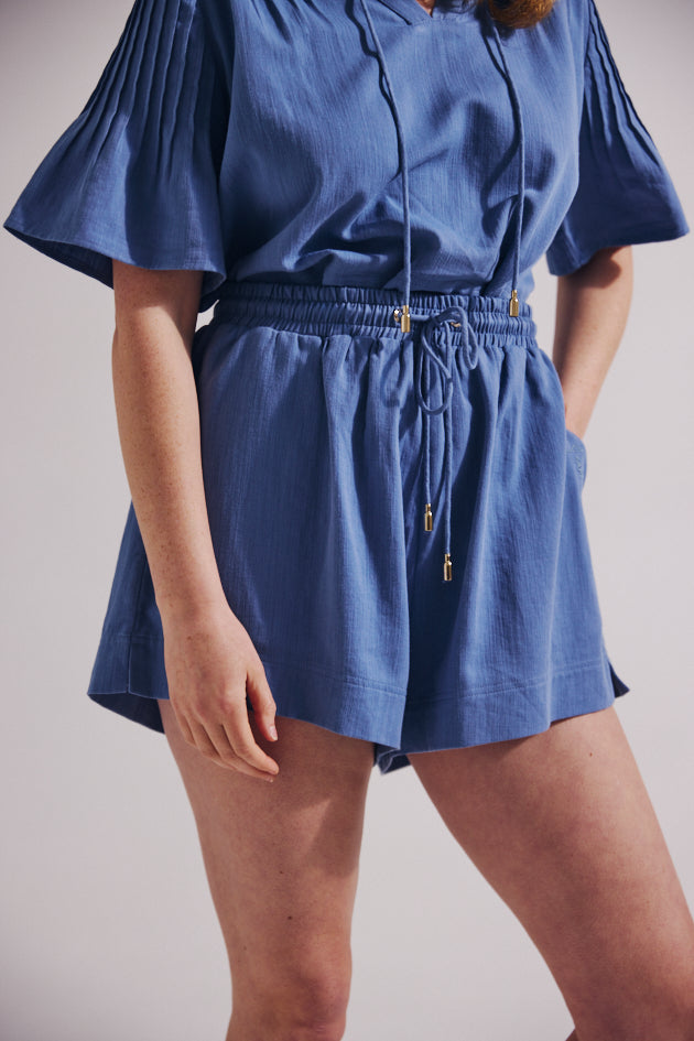 Blue romper worn by a person on a plain background