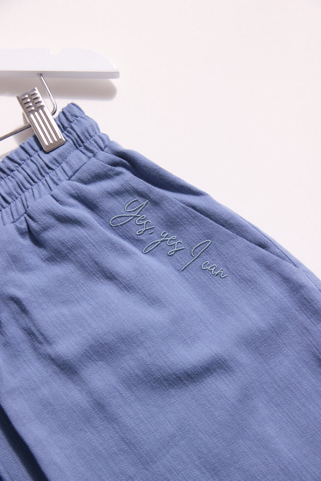 Blue pants with text embroidery on a white background