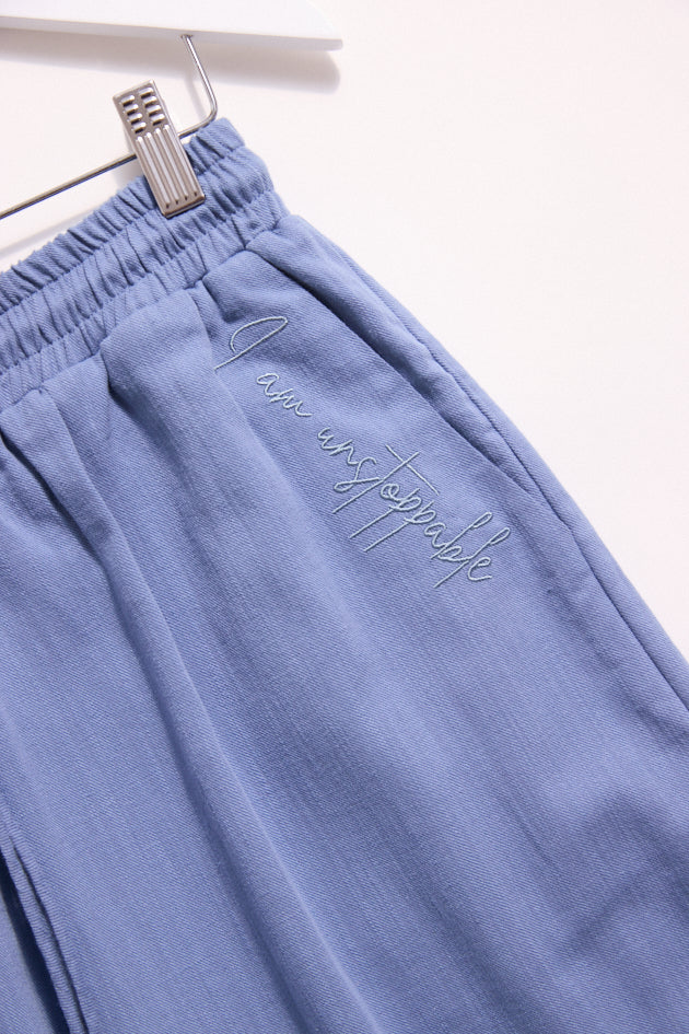 Blue pants with text embroidery on a white background