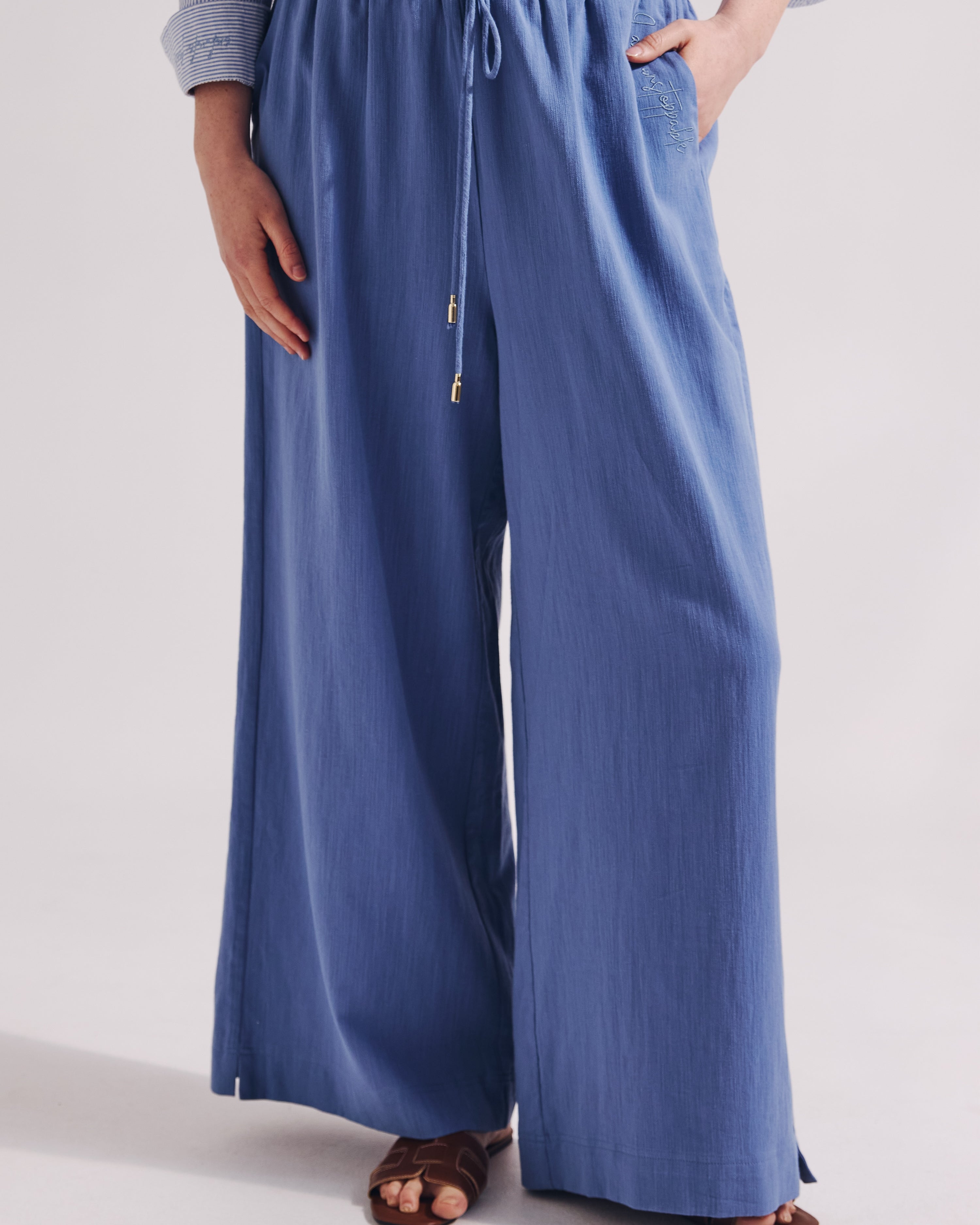 Person wearing blue wide-leg pants on a plain background