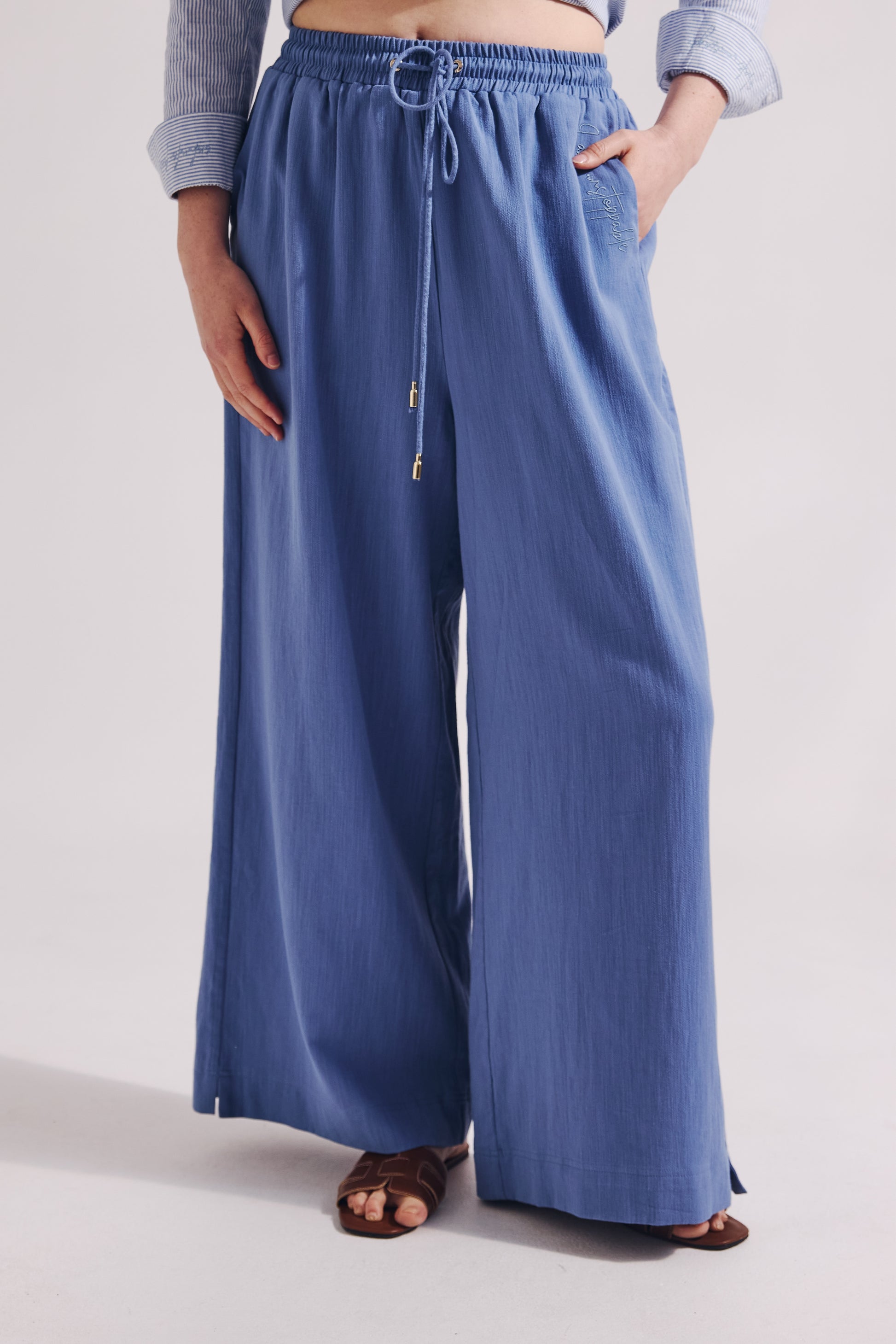Person wearing blue wide-leg pants on a plain background