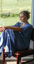 Woman sitting on a chair by a window holding a bowl, with a scenic view outside.