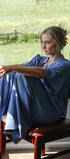 Woman sitting on a chair by a window holding a bowl, with a scenic view outside.