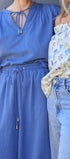 Two women wearing a blue dress and floral top with jeans.