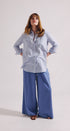 Woman wearing a light blue shirt and wide-leg pants on a white background