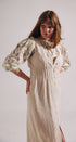Woman wearing a floral blouse and beige dress with a white background