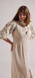 Woman wearing a floral blouse and beige dress with a white background