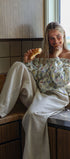 Woman sitting on a kitchen counter eating a croissant