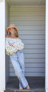 Woman wearing a floral top and jeans standing in a doorway.
