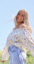 Woman wearing a floral blouse and jeans against a blue sky