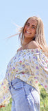 Woman wearing a floral blouse and jeans against a blue sky
