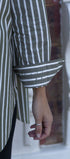 Close-up of a person wearing a green and white striped shirt with a blurred background