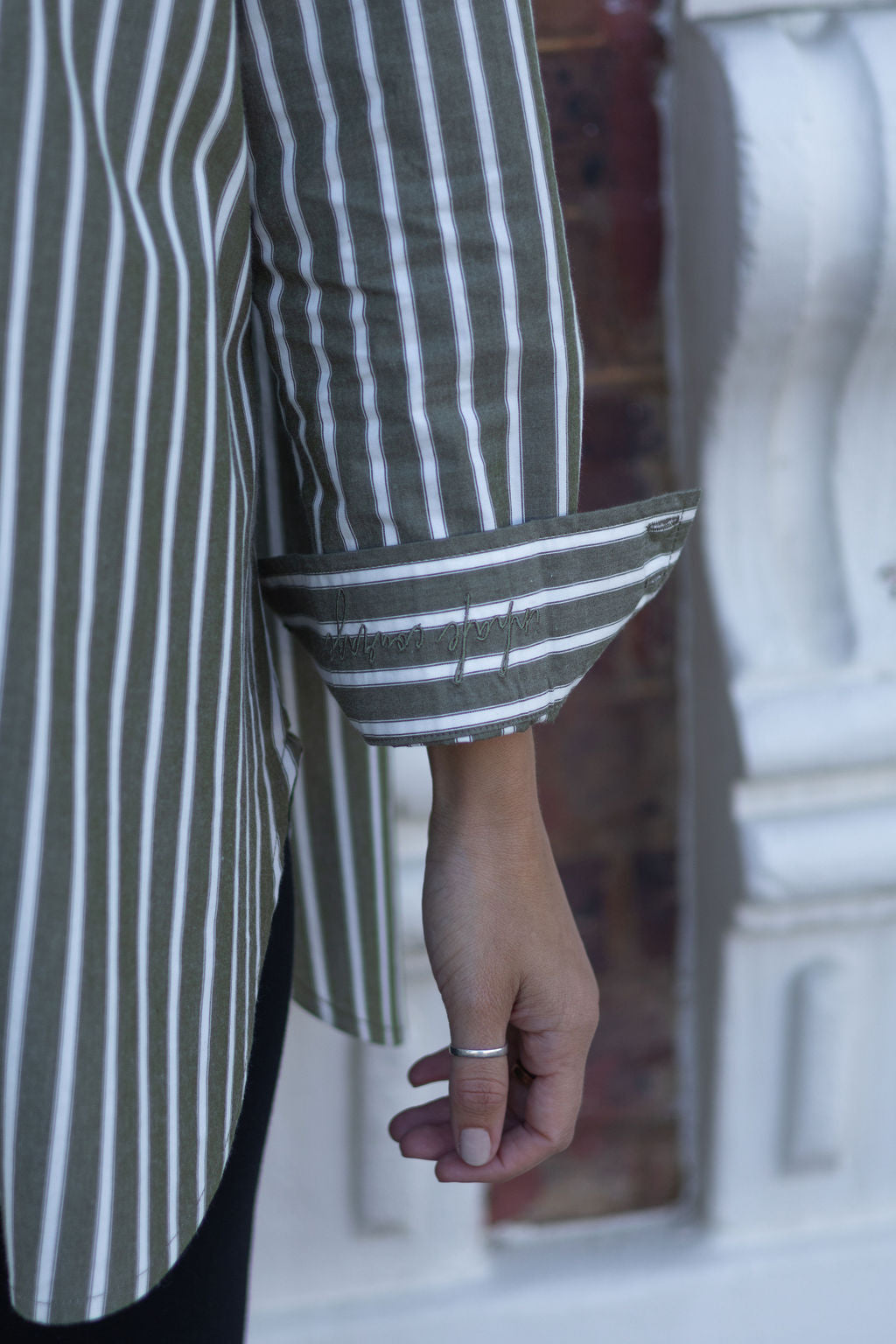 Close-up of a person wearing a green and white striped shirt with a blurred background