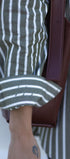 Close-up of a person wearing a green and white striped shirt with a brown leather bag.