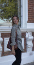 Woman holding a coffee cup and a brown bag in front of a brick building.