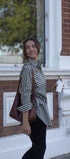 Woman holding a coffee cup and a brown bag in front of a brick building.