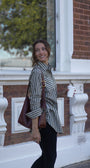 Woman holding a coffee cup and a brown bag in front of a brick building.