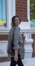 Woman standing outside a building holding a cup and a bag
