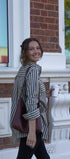 Woman standing outside a building holding a cup and a bag