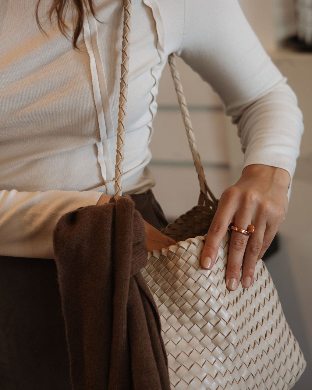 Person holding a woven handbag with a neutral background