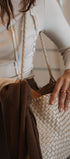 Person holding a woven handbag with a neutral background