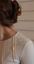 Close-up of a person wearing a beige garment with visible text, against a neutral background.