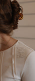 Close-up of a person wearing a beige garment with visible text, against a neutral background.