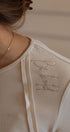 Close-up of a beige garment with 'Du Jour' embroidery on a neutral background