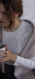 Woman holding a mug with a white shirt and beige cardigan against a light background