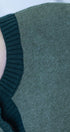 Close-up of a green knitted sweater with embroidered affirmation.