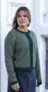 Woman wearing a green sweater standing in front of a white door.