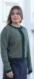 Woman wearing a green sweater standing in front of a white door.